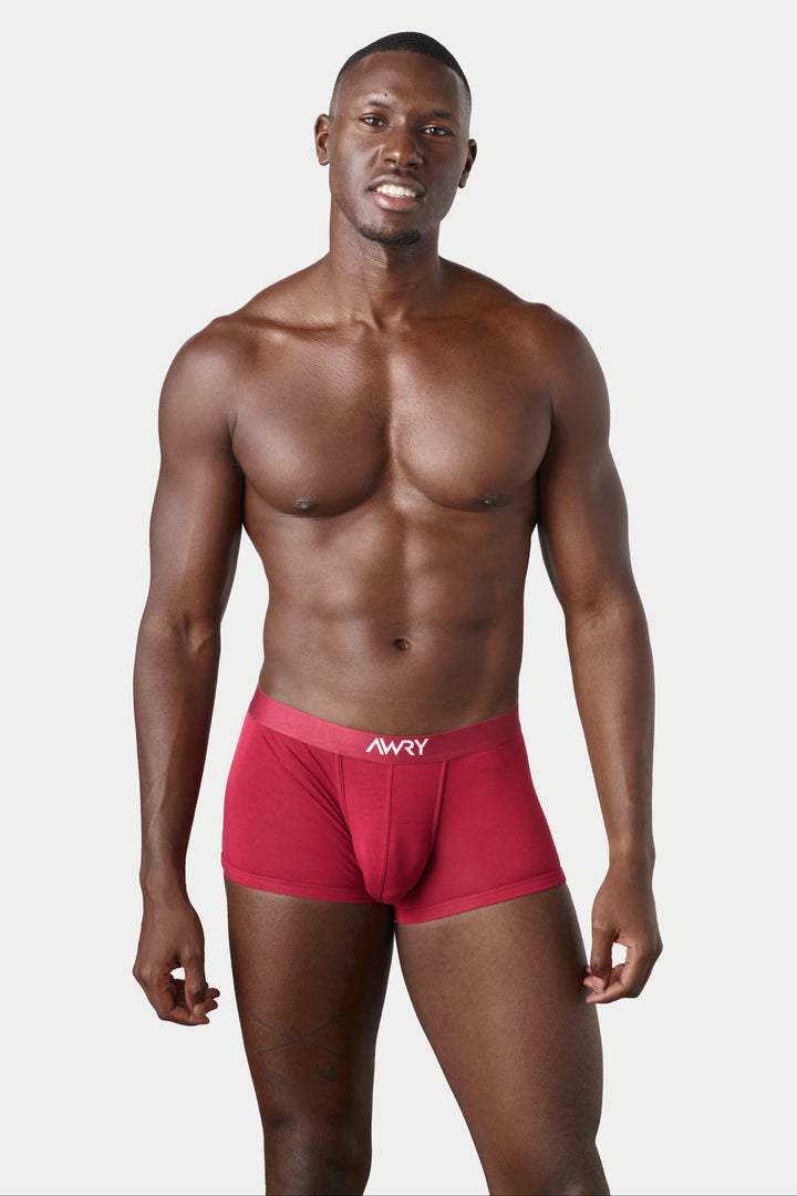 A shirtless man modeling red boxer briefs with a white &