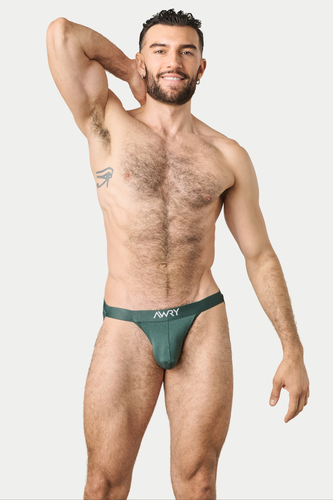 A shirtless man modeling a dark green jockstrap with a white 'Navy' brand logo on the waistband, posed against a solid light gray background.