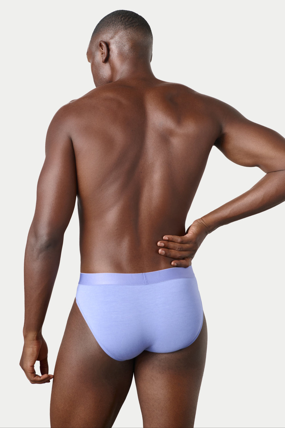 A man shown from the back wearing light lavender blue underwear, photographed against a clean light gray studio background.