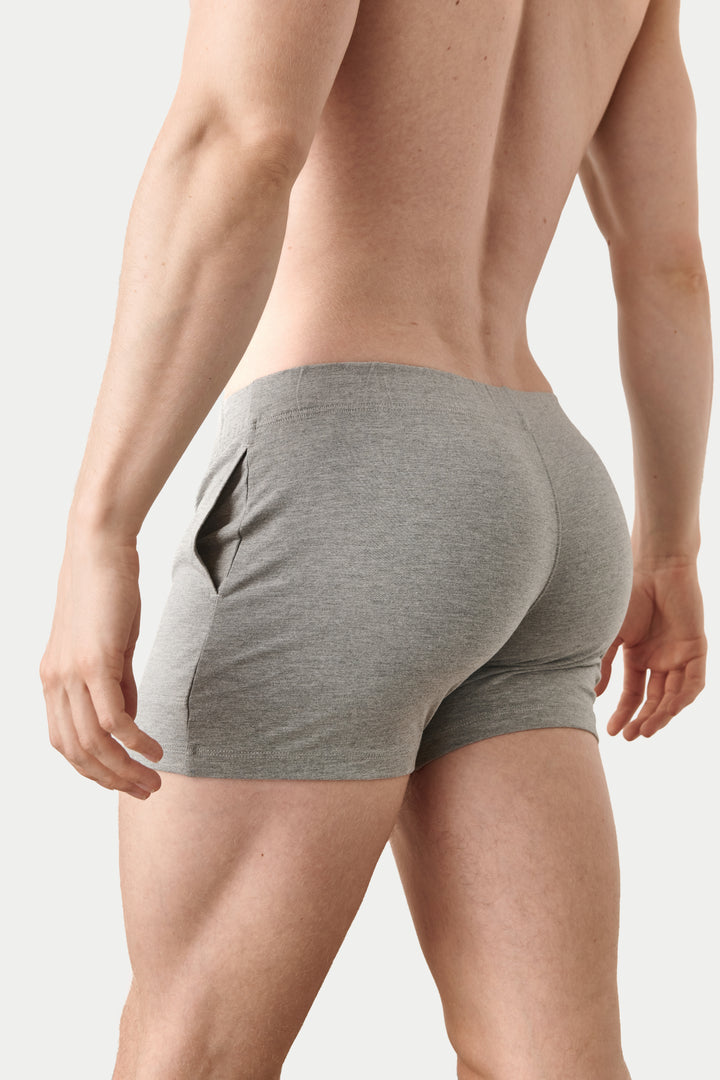 Rear view of a man wearing heather gray athletic briefs against a light gray studio background.