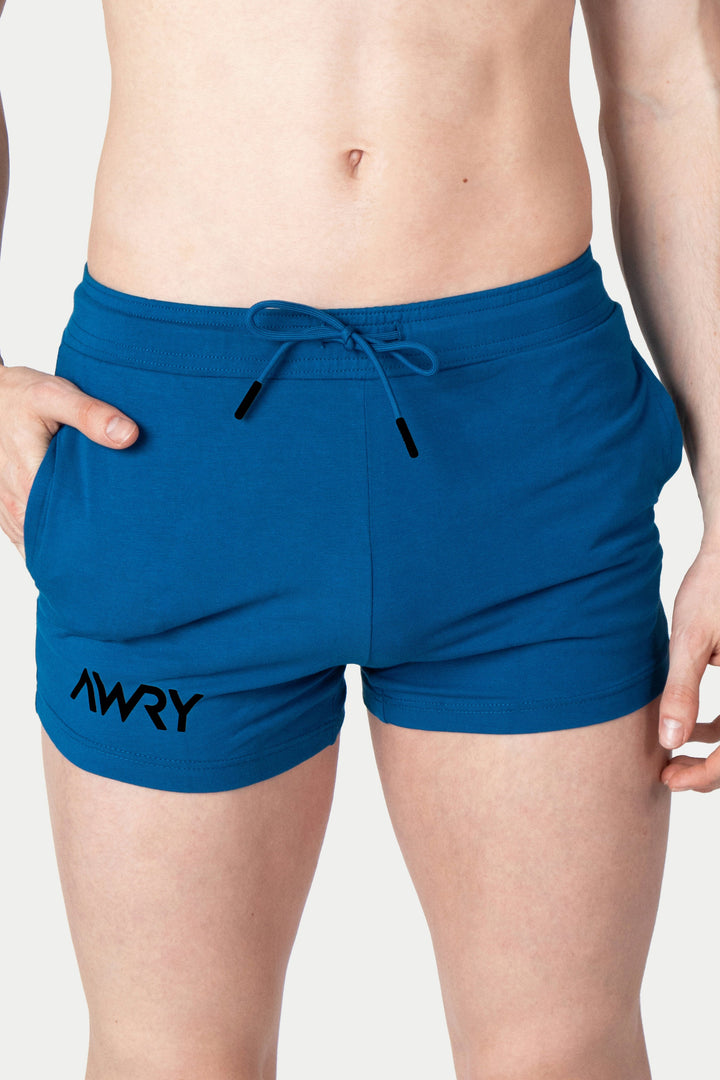 Cerulean blue shorts with drawstring waist, side pockets, and black logo text on leg.