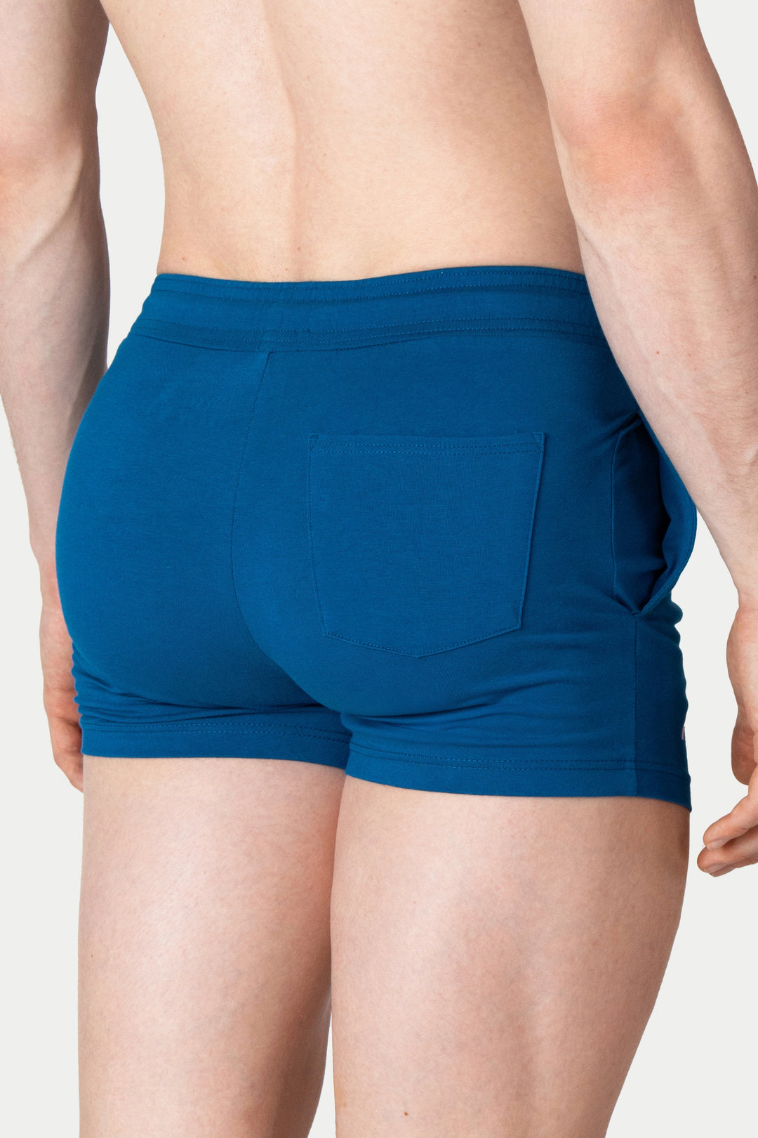 Cerulean blue shorts with elastic waistband and back pocket, shown from rear view on male model.