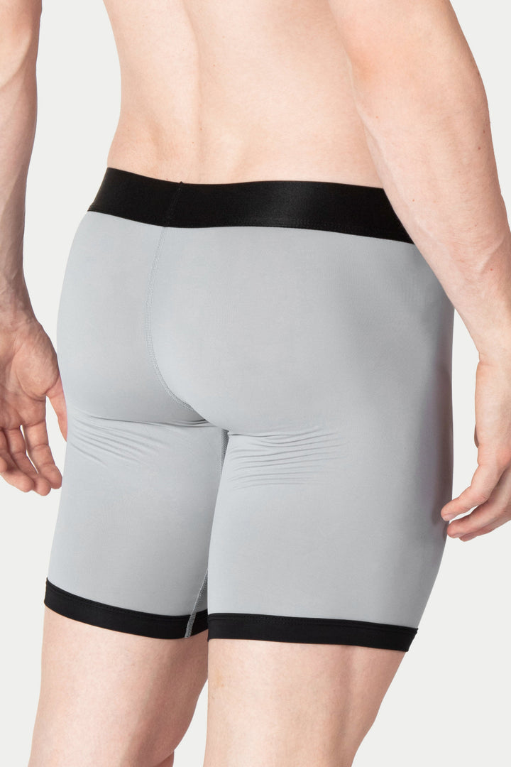 Gray boxer briefs with black elastic waistband and leg cuffs, shown on model from waist down.
