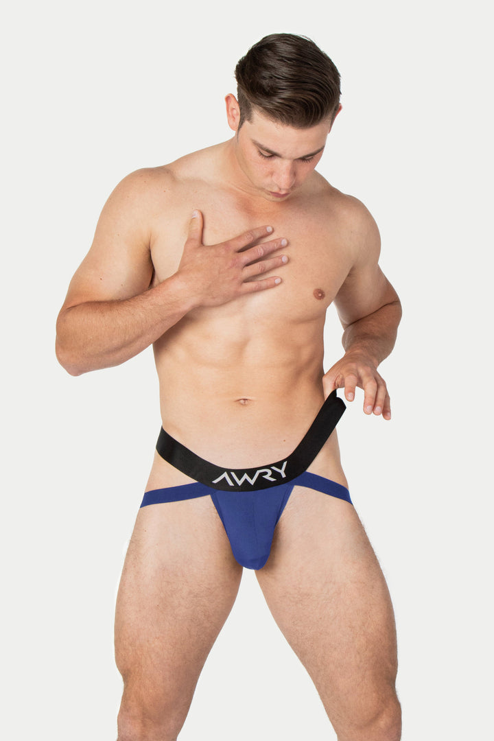 Navy jockstrap with black waistband and "AWRY" branding worn on male model.