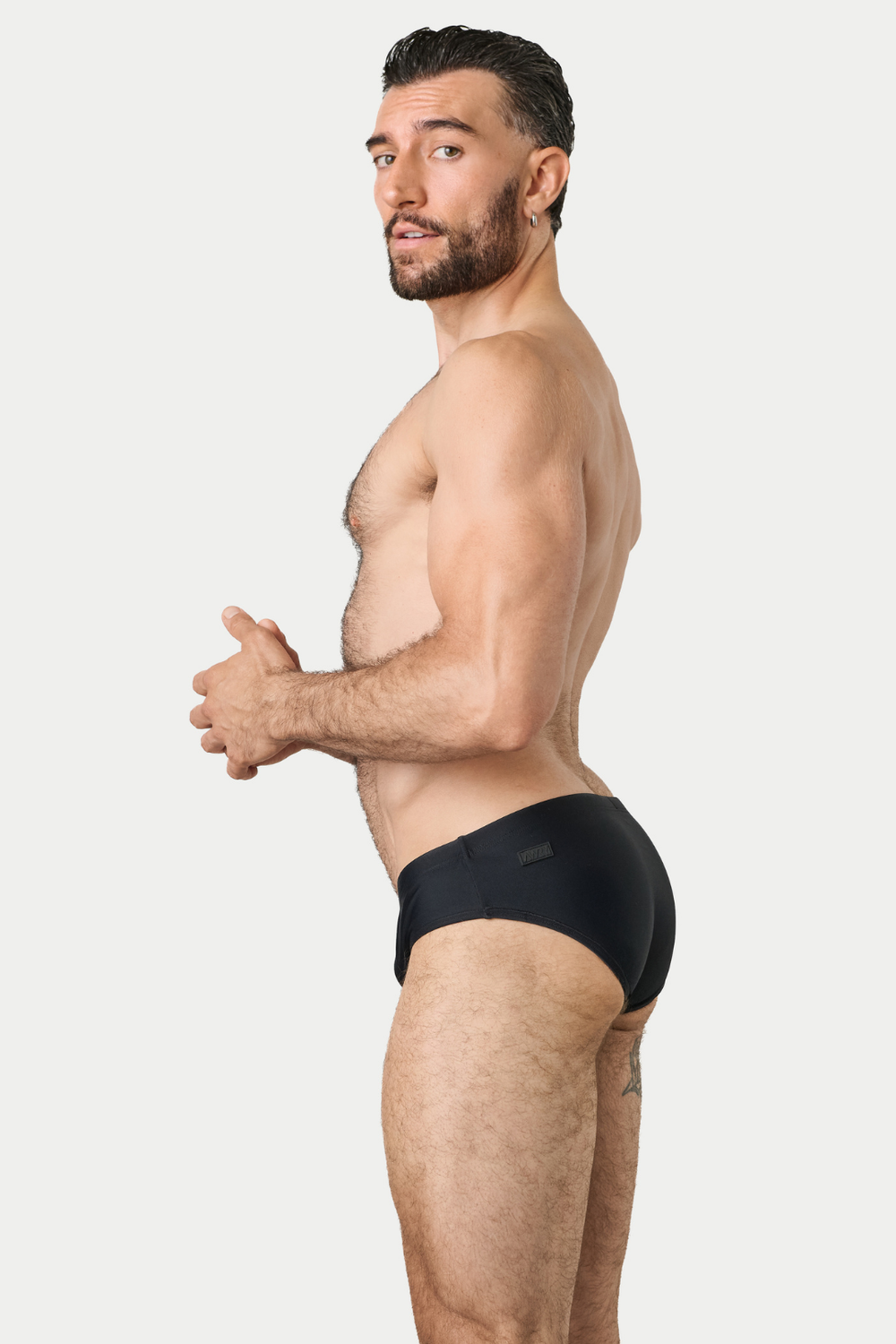 Man wearing black BARTON Classic Swim Brief, side view against white background.