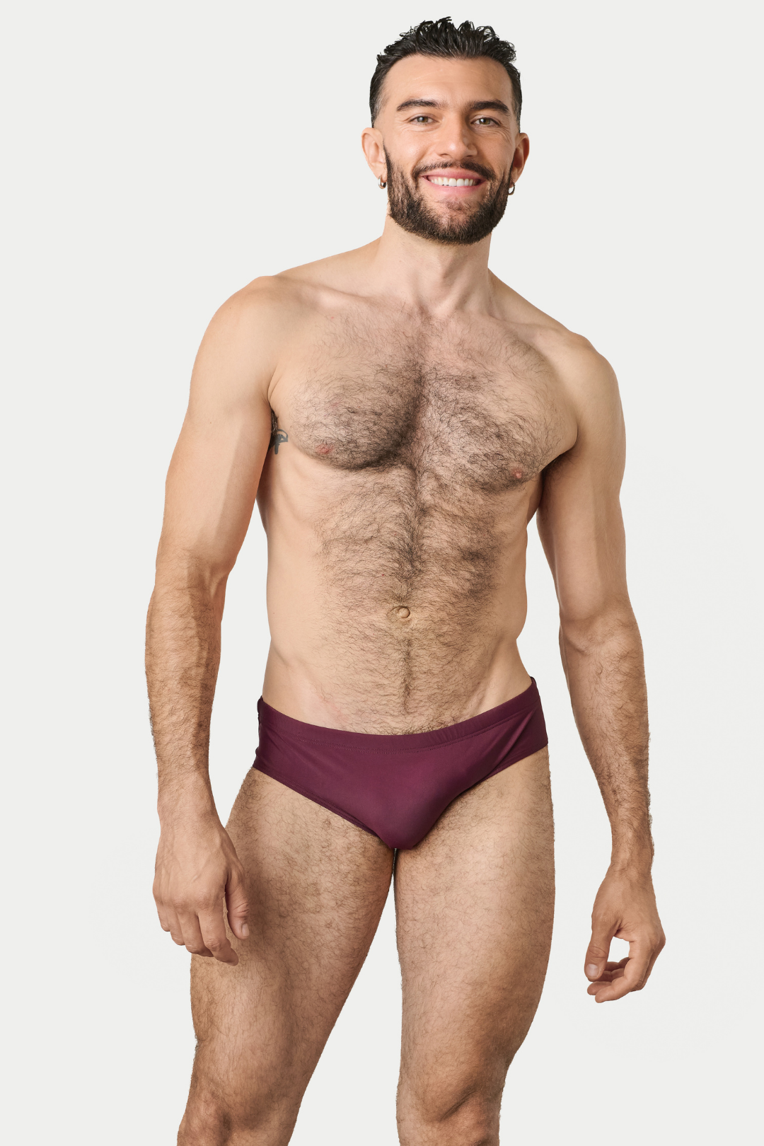 Man wearing burgundy swim brief with classic brief cut and low waistband.
