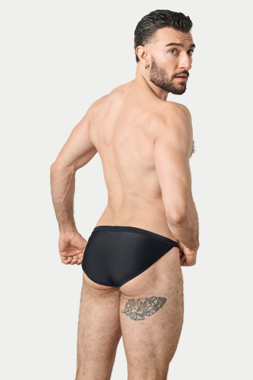 Man wearing black swim tanga, shown from behind.