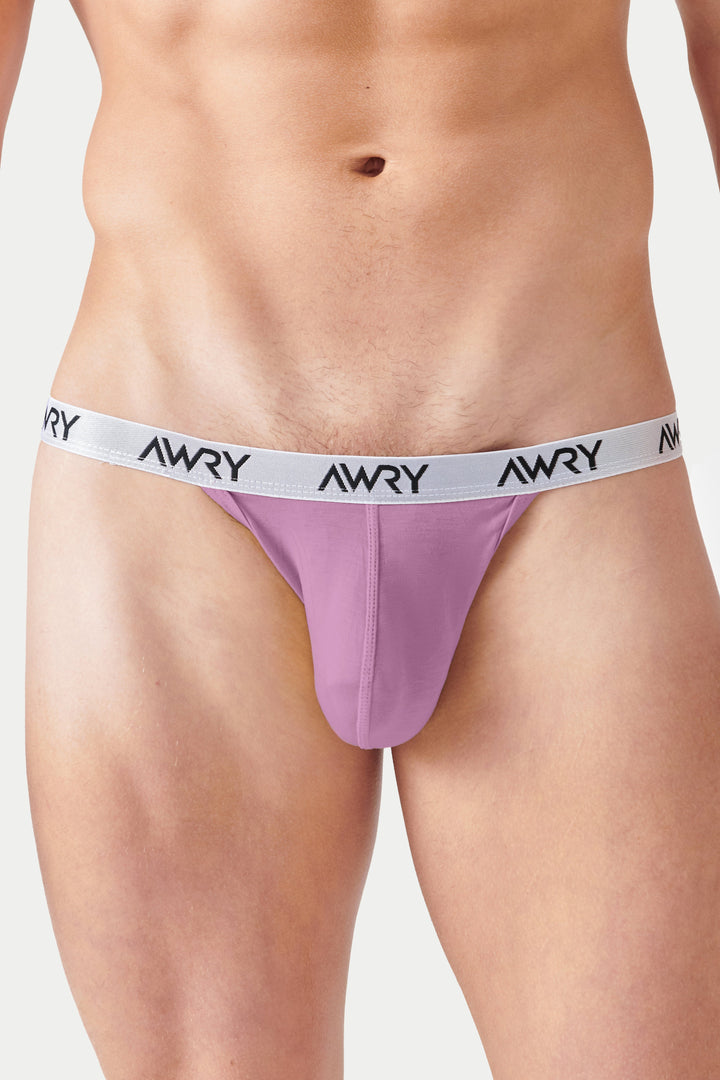 Pale pink tanga briefs with white AWRY waistband displayed on model.