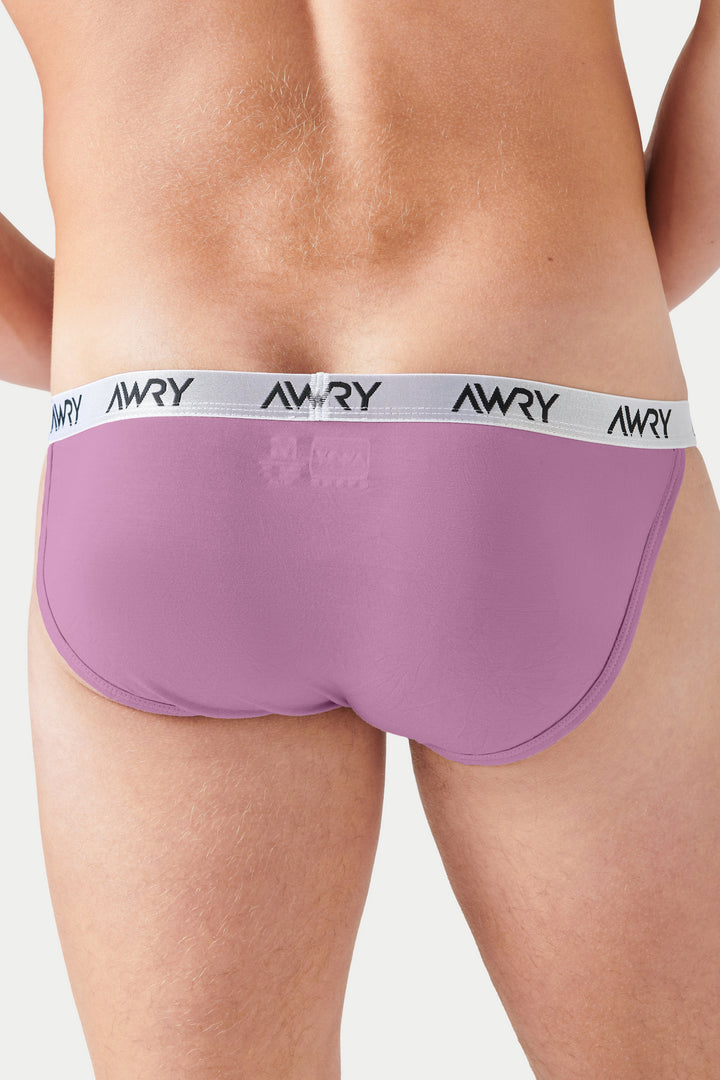 Pale pink tanga briefs with white waistband featuring "AWRY" text, shown on a model from waist down.