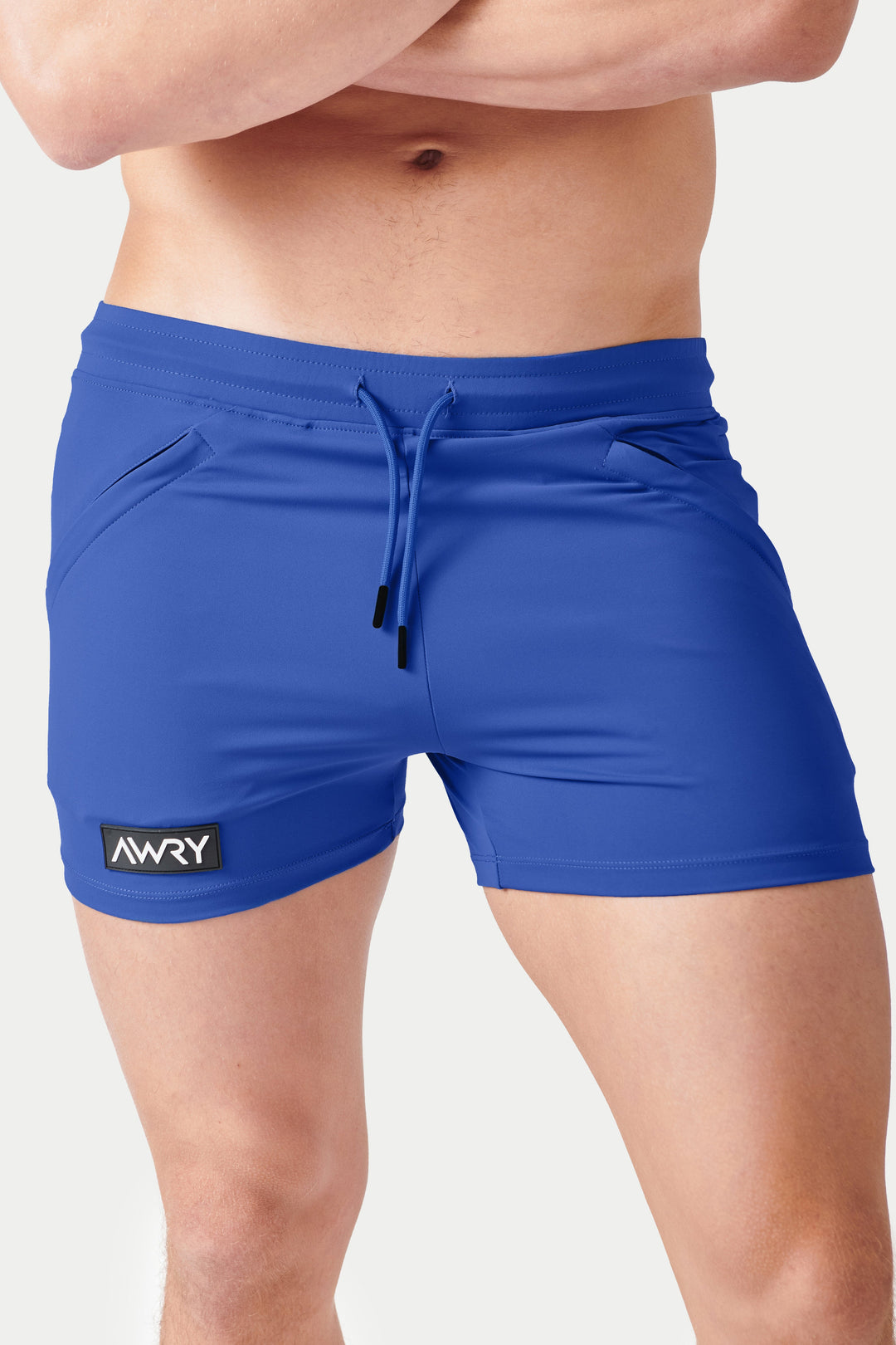Cobalt blue shorts with drawstring waistband, side pockets, and AWRY logo patch on leg.