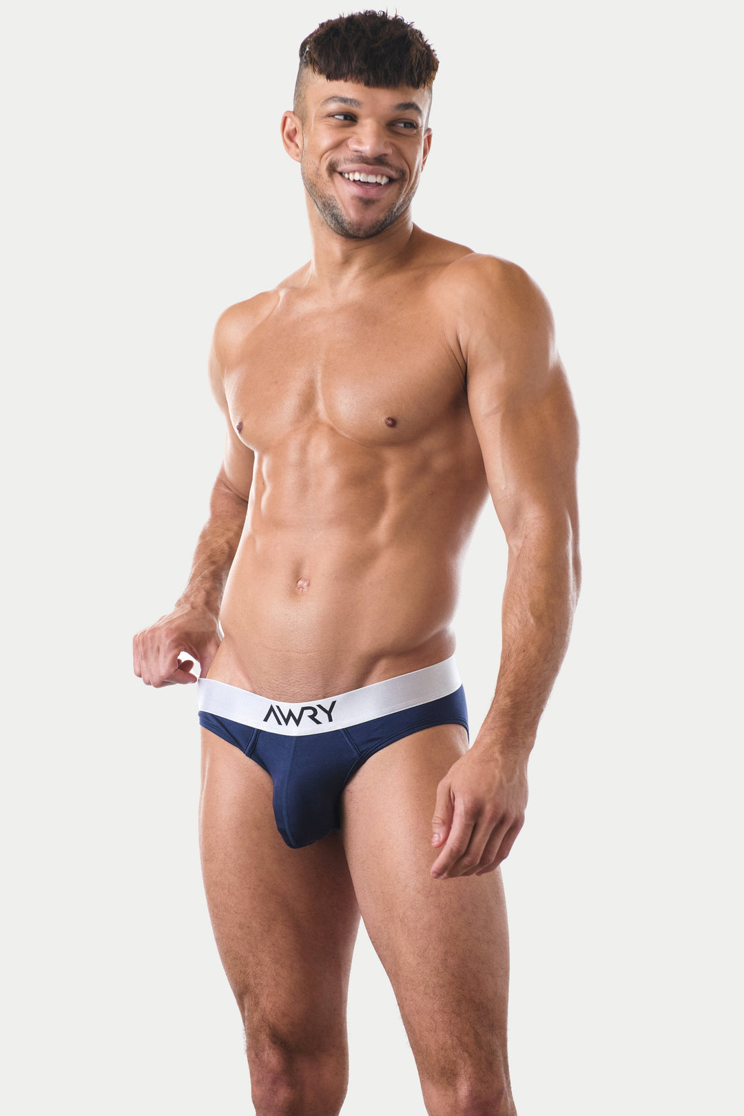 Man wearing navy briefs with white waistband labeled AWRY.