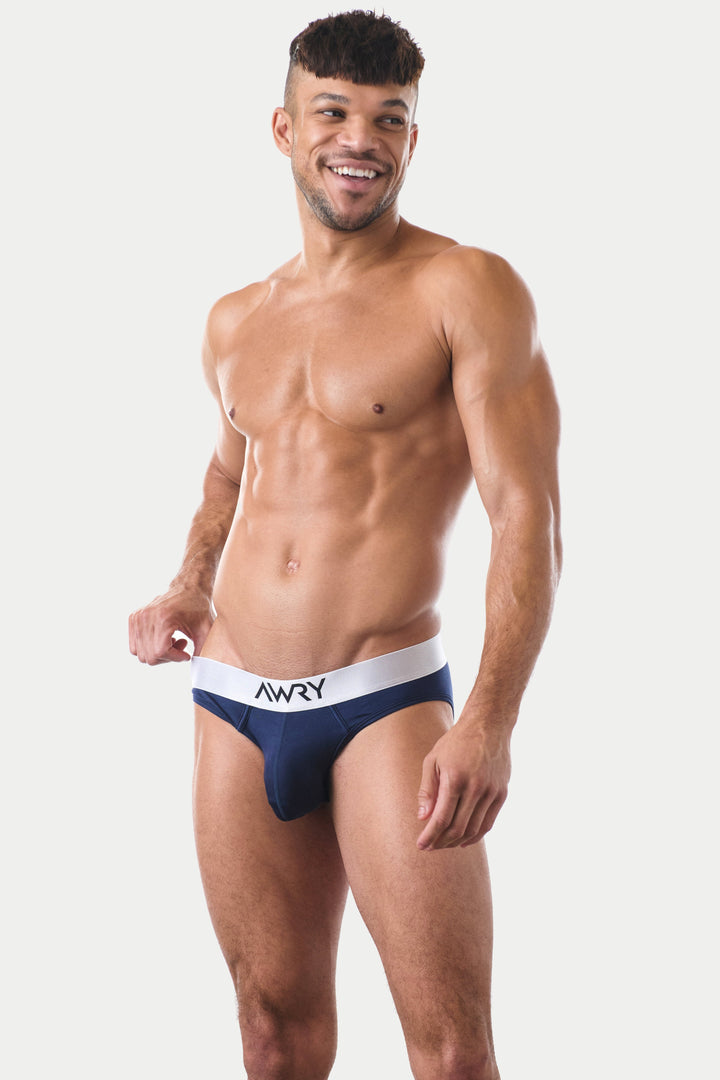 Man wearing navy briefs with white waistband labeled AWRY.