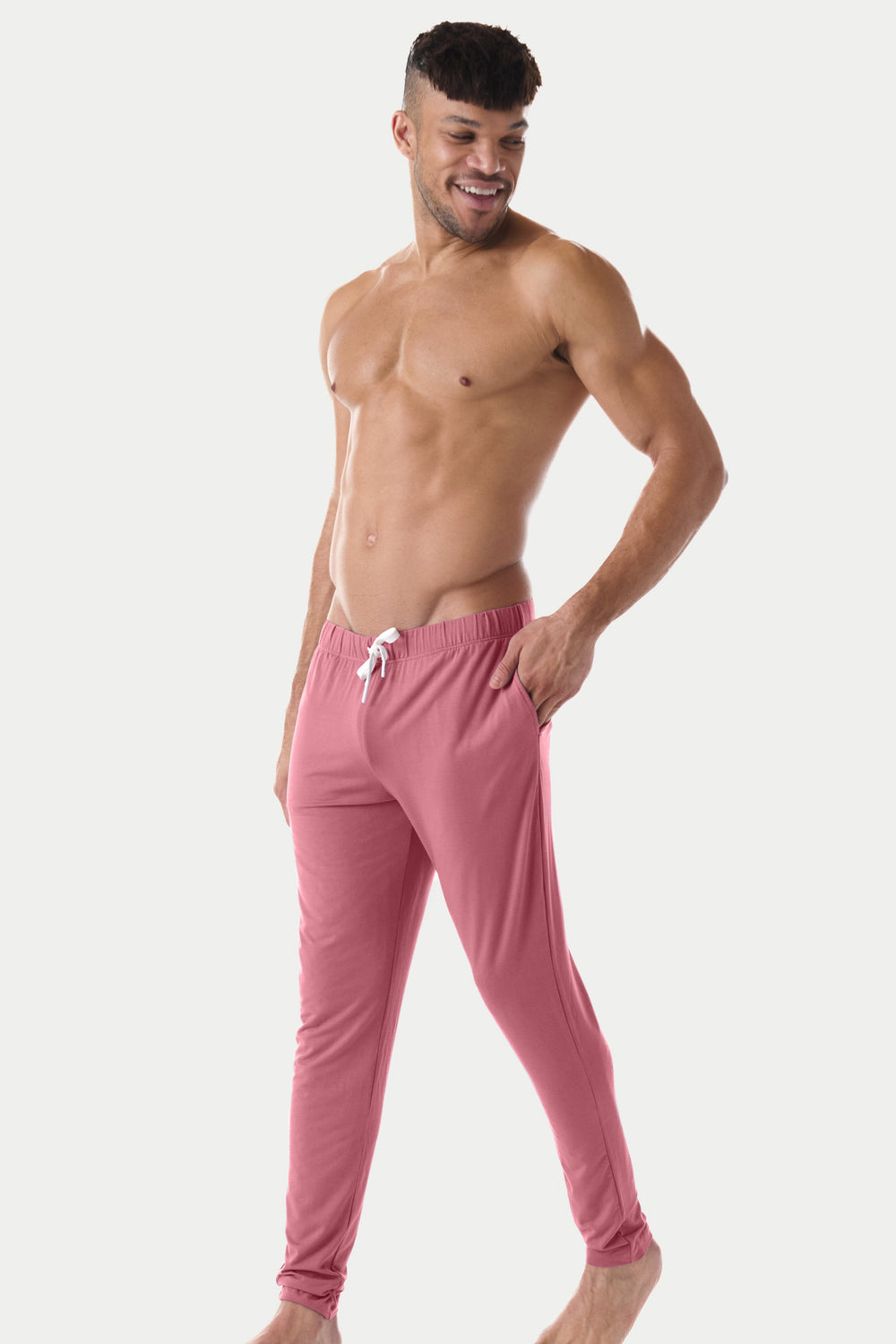 Man wearing blush red lounge pants with drawstring waist and ribbed ankles.