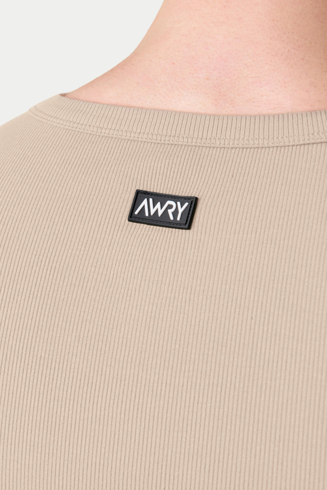 Sand-colored ribbed tank top with crew neckline and black brand label on chest.