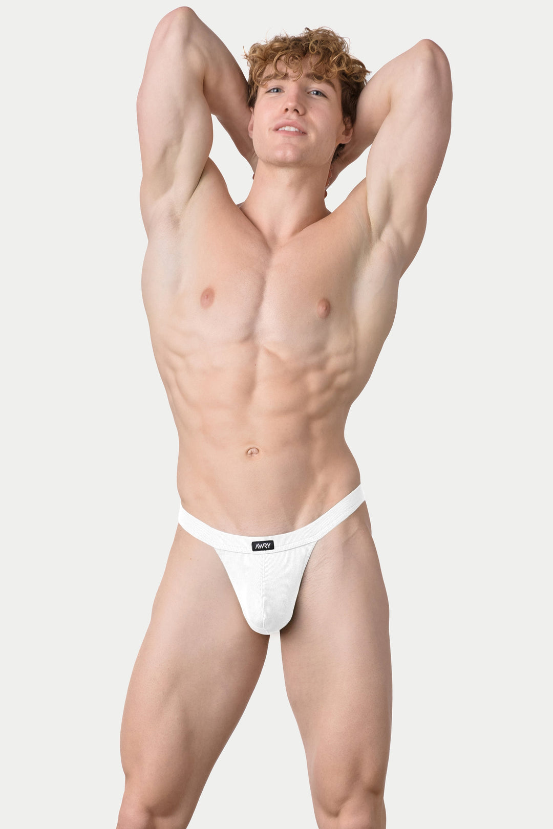 Man wearing white ribbed thong with branded waistband, hands behind head.