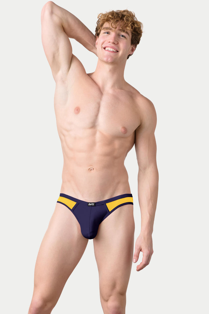 Man wearing navy bikini briefs with yellow side stripes and AERO branding.
