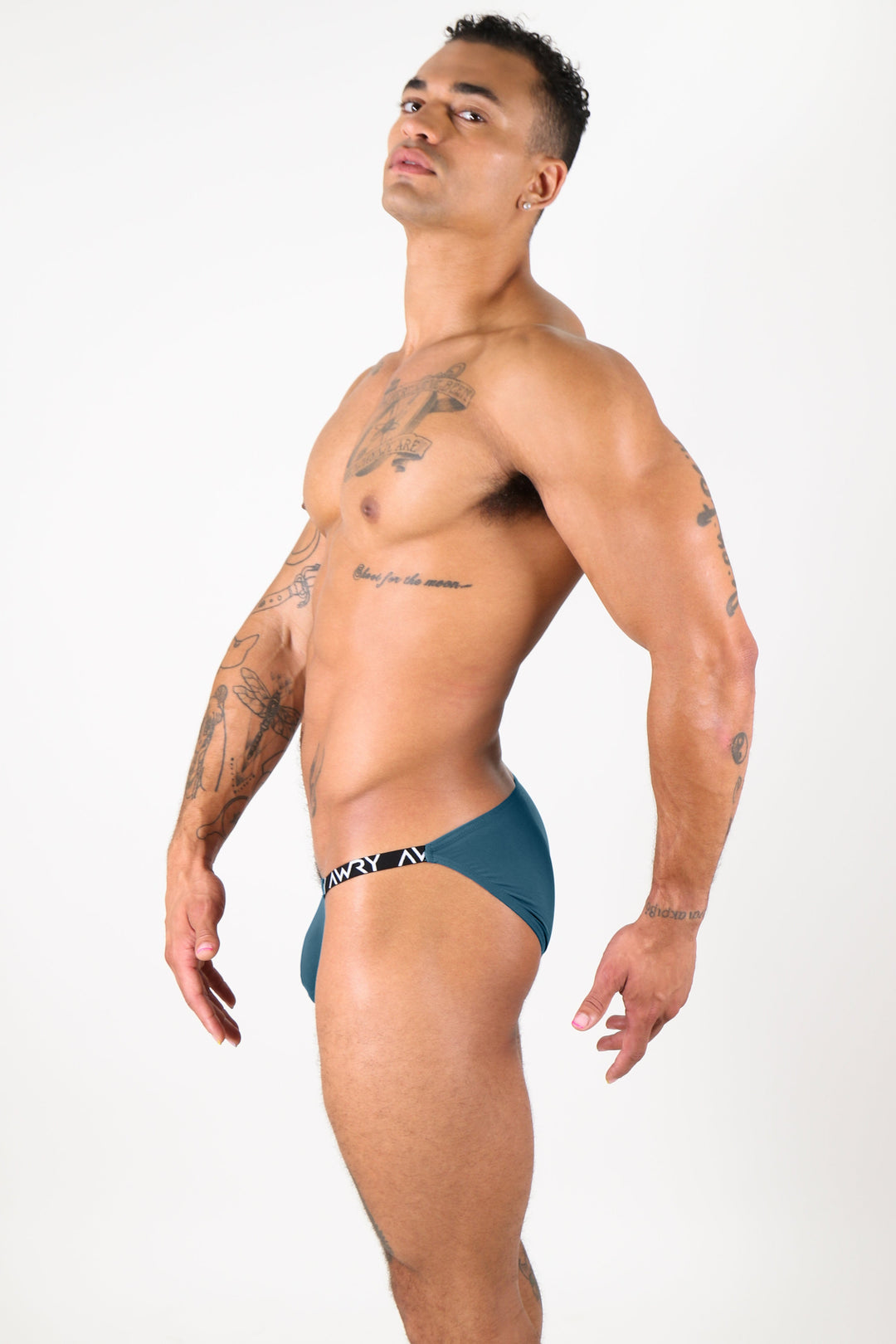 Man wearing ocean blue bikini briefs with elastic waistband, shown from the side.